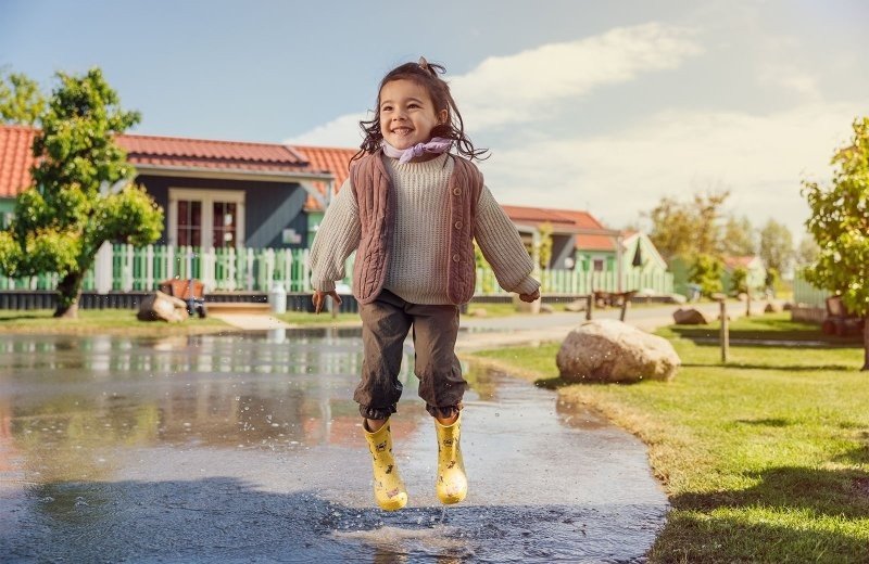 Peuter springt met gele laarzen in een plas bij Molenwaard